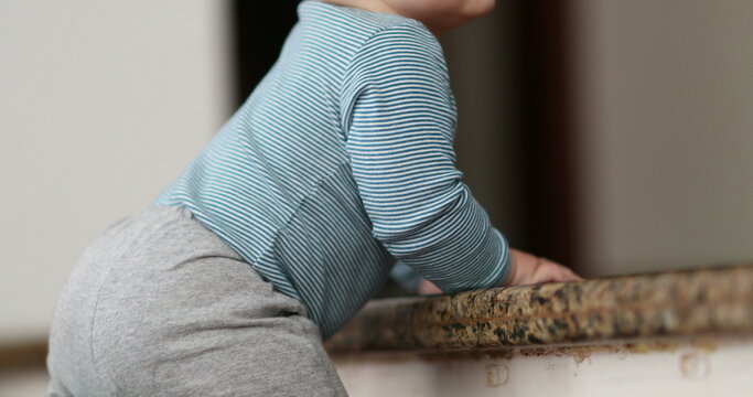 Baby holding stair learning to climb doorstep