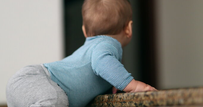 Baby holding to doorstep stair observing the world. Toddler development