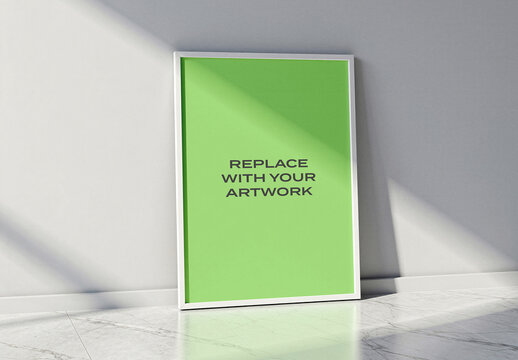 Vertical framed poster mockup leaning against a light gray wall in modern interior, realistic art presentation with natural marble floor, and soft shadows, graphic design template