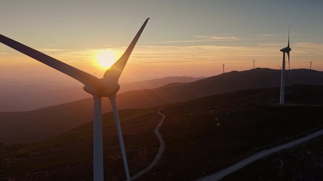 Wind turbines across mountain ridges at sunset 