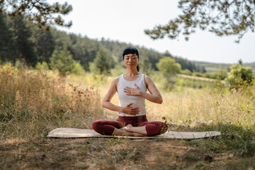 Fototapeta premium Woman practicing mindful breathing meditation in nature