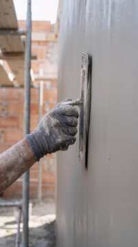 Worker installs or finishes a metal surface on a building exterior using hand tools during construction.
