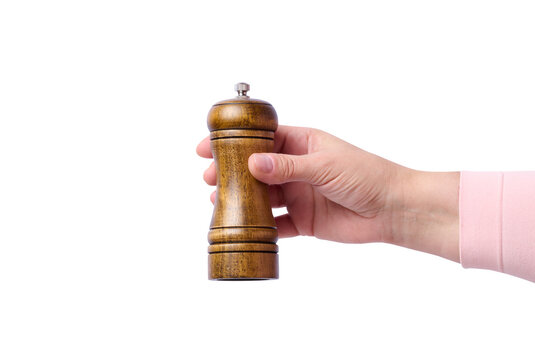 Female hand holding wooden pepper mill on isolated background.