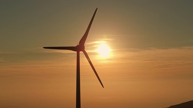 Wind turbine silhouette against golden sunset