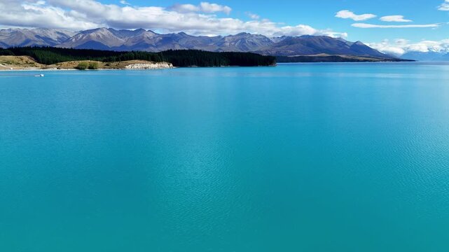Aerial view of turquoise Lake Pukaki with mountain range and blue sky in New Zealand. 
