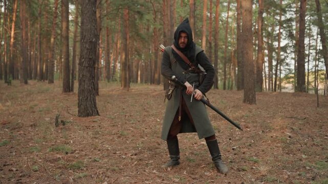 Hooded figure in medieval-style cloak moves through sparse pine woodland, handling crossbow while shifting from cautious forward step to upright ready stance with alert focus, with hooded, archer