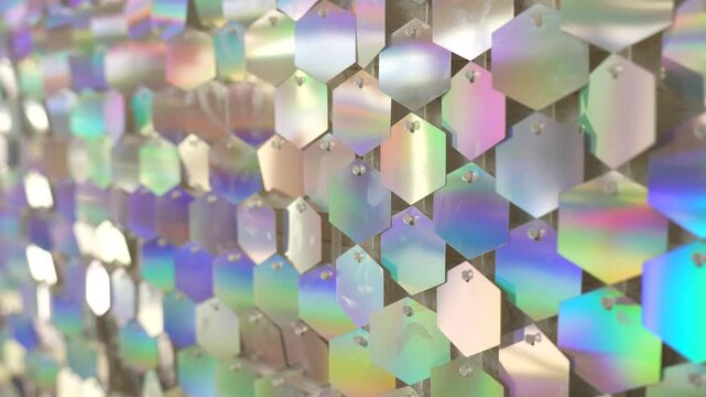 Holographic hexagon sequins shimmer on a reflective decorative wall panel creating iridescent light patterns and modern geometric textures for interior design backdrops