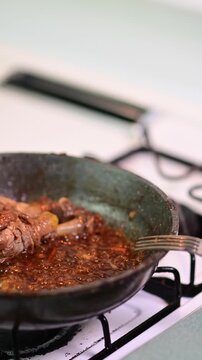 Home made chicken on a frying pan boiling souse, man cooking, vertical authentic real life cooking video