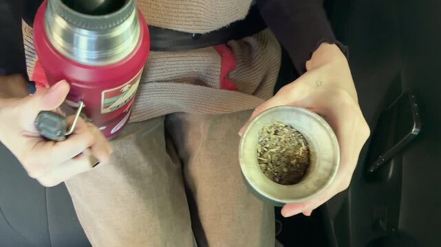 Hands Preparing Traditional South American Warm Infusion, Yerba Mate, On the Road in the Car, Argentina. Typical hot drink, Uruguay, Paraguay, Brazil. 