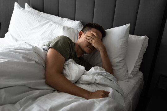 Young man waking up in the morning feeling tired suffering from insomnia bad sleep	