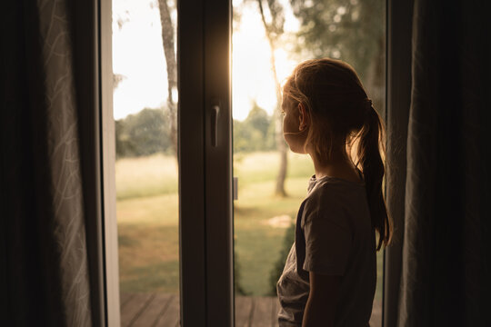 Little Girl Looking Out Window at Warm Morning Sunlight