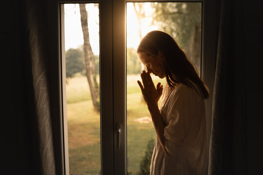 Religious worship, and spiritual enlightenment concept. Woman saying a prayer at sunrise.	