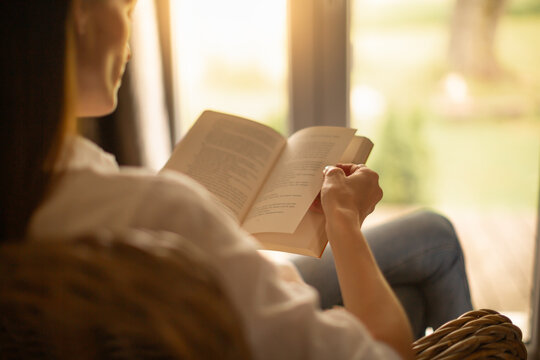Woman at home relaxing by the window reading and enjoying a peaceful morning 	