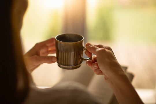 Person relaxing at home reading book feeling relaxed on a cozy winter morning enjoying cup of hot tea coffee	