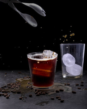 Refreshing iced coffee cocktail with orange slice ice cubes vintage manual grinder and scattered roasted coffee beans on dark surface
Keywords