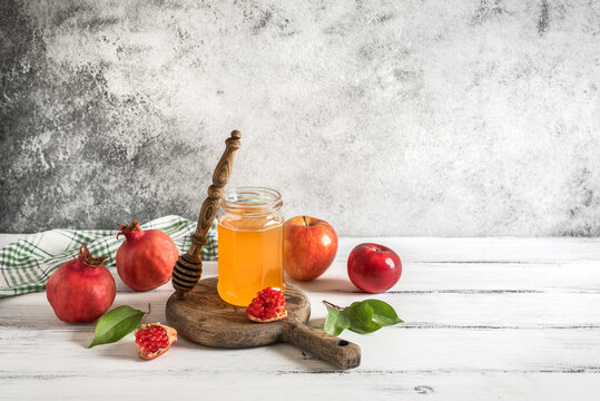 Jewish New Year Rosh Hashanah, Apples, pomegranate and honey on a white rustic background. Side view, copy space