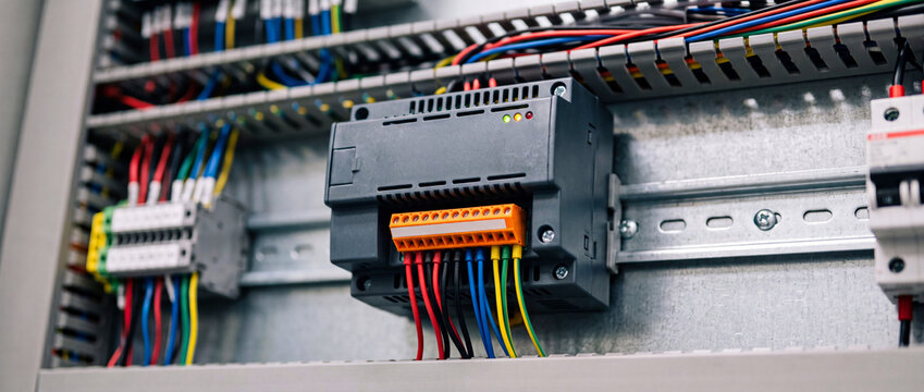 Industrial electrical control panel with multi-colored wiring and mounted relay module on DIN rail