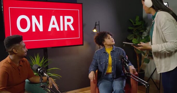 African American hosts reacting to producer cue, adjusting mics in studio preparing ON AIR sign