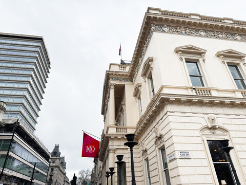 Neoclassical white stone building with columns and Institute of Directors IoD flag on Waterloo Place, London UK