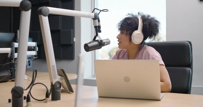 African podcast hosts in recording studio, woman leaning to mic initiating conversation, recording