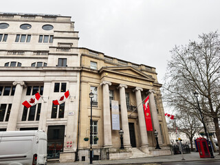 Fototapeta premium Historic Canada building with flags and neoclassical columns in central London, UK on overcast day
