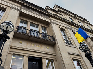 Fototapeta premium Canada embassy building facade with ukrainian flag and lamps in London, UK photographed from below