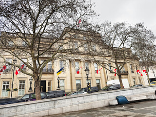 Fototapeta premium Canadian embassy building with flags and pedestrians outside in London, UK on an overcast day