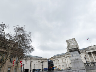 Fototapeta premium National Gallery and Trafalgar Square scene with flags and sculpture in London, UK on overcast day