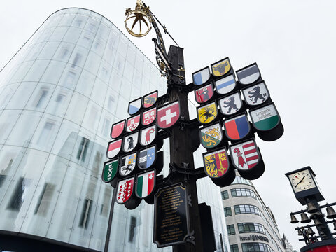 Historic Swiss Court heraldic coat of arms sign and street clock beside modern glass building in London, UK