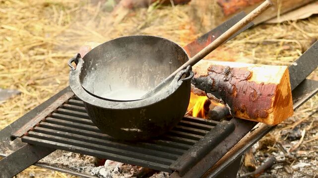 A pot sits on a grill next to a piece of bread, perfect for a backyard barbecue or outdoor gathering