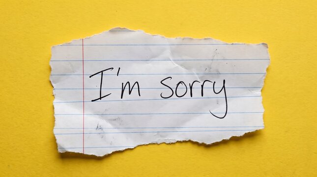 Handwritten I'm sorry note on torn paper. Apology message on ripped notebook scrap. Sad confession on yellow background.