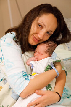Mother hugging her newborn baby boy in bed in hospital