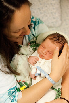 Mother hugging her newborn sleeping baby boy in bed in hospital