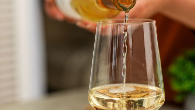 White wine pouring into elegant tasting glass