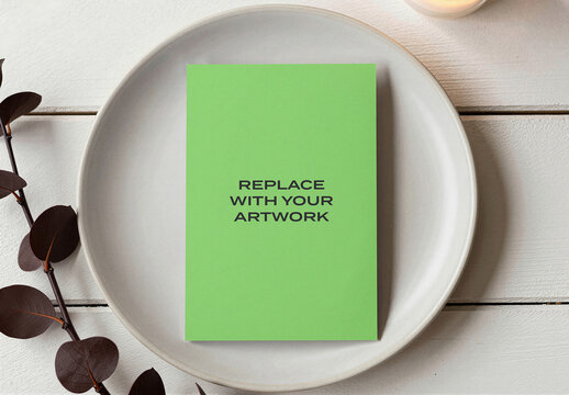 Vertical brochure mockup on a ceramic plate with green background, clean minimalist table setting, natural light, indoor plant, branding display, stationery presentation, template