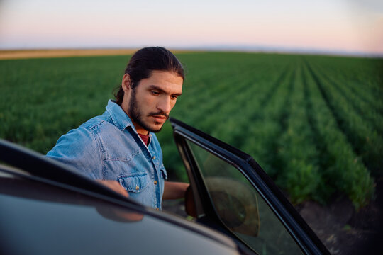 Young farm owner getting into his truck in field.
