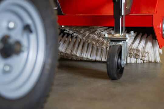 Street sweeper rotary brush assembly showcasing thick synthetic bristles and rolling caster wheels attached to a heavy machinery housing unit