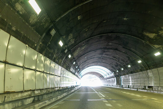 出口の光へ続く高速道路トンネルとアスファルト道路
