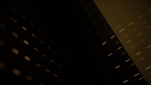 Dark abstract composition showing light dots creating a grid pattern on a surface, with a prominent diagonal shadow