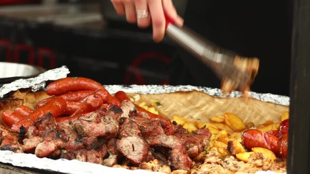 A close-up of a person cutting meat with tongs