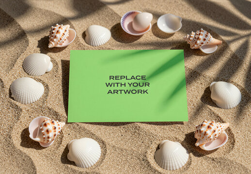 Rectangular card mockup displayed on sandy beach with seashells and palm leaf shadows, natural sunlight illumination, outdoor scene, flat lay top view presentation, stationery design template