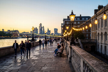 Obraz premium Riverfront promenade at dusk with string lights walkers and a city skyline