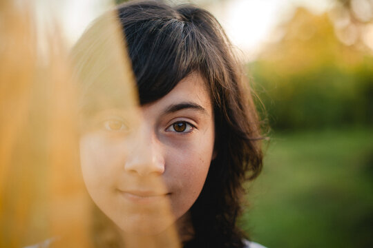 Close up portrait of a smiling young girl looking at the camera outdoors in warm natural light