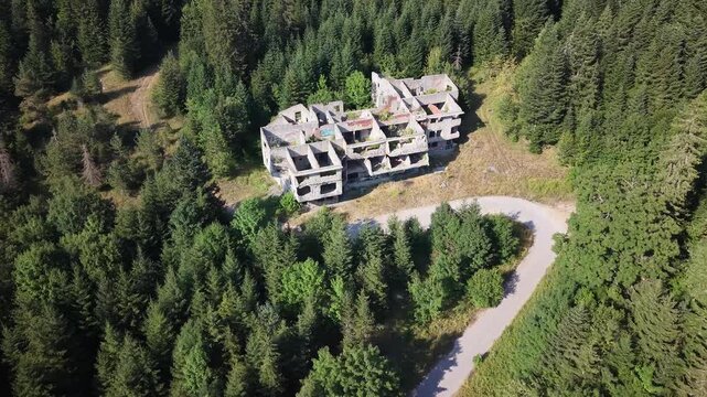 Aerial Flyover of Abandoned Destroyed Olympic Village Structure in Dense Pine Forest on Igman Mountain, Bosnia and Herzegovina