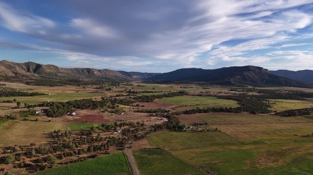 Aerial of rural Colorado desert valley landscape in Mancos with rolling hills and mixed agricultural fields and residential properties