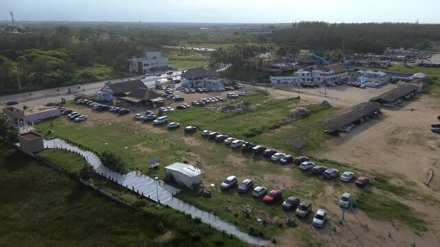 Miramar Beach parking area crowded with vehicles, beachgoers and palapas along the busy Gulf of Mexico shoreline