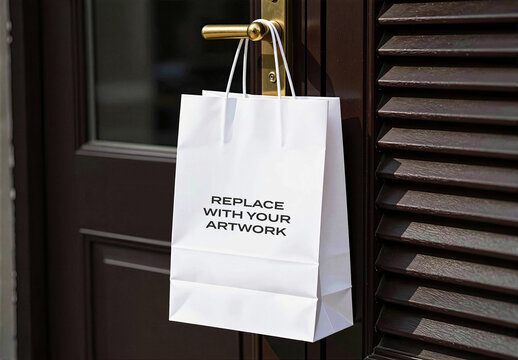 Paper shopping bag mockup hanging on a brass door handle, realistic retail packaging presentation with dark wood and louvered window shutter background