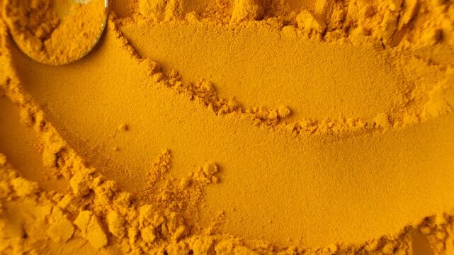 Top view of vibrant yellow turmeric powder being stirred with a spoon