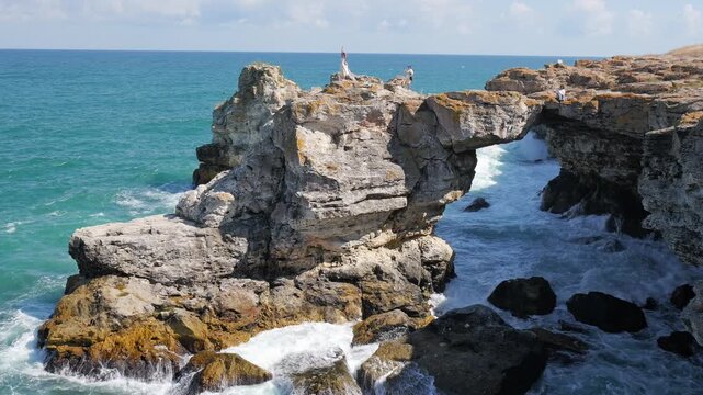 People posing on the famous rocky arch in tyulenovo, bulgaria