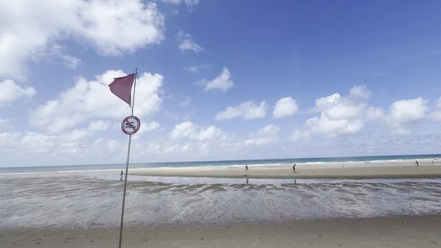 Le Porge, Gironde, France - August 2026: Red no-swimming flag and warning sign in front of a ba&iuml;ne channel on the Atlantic beach.